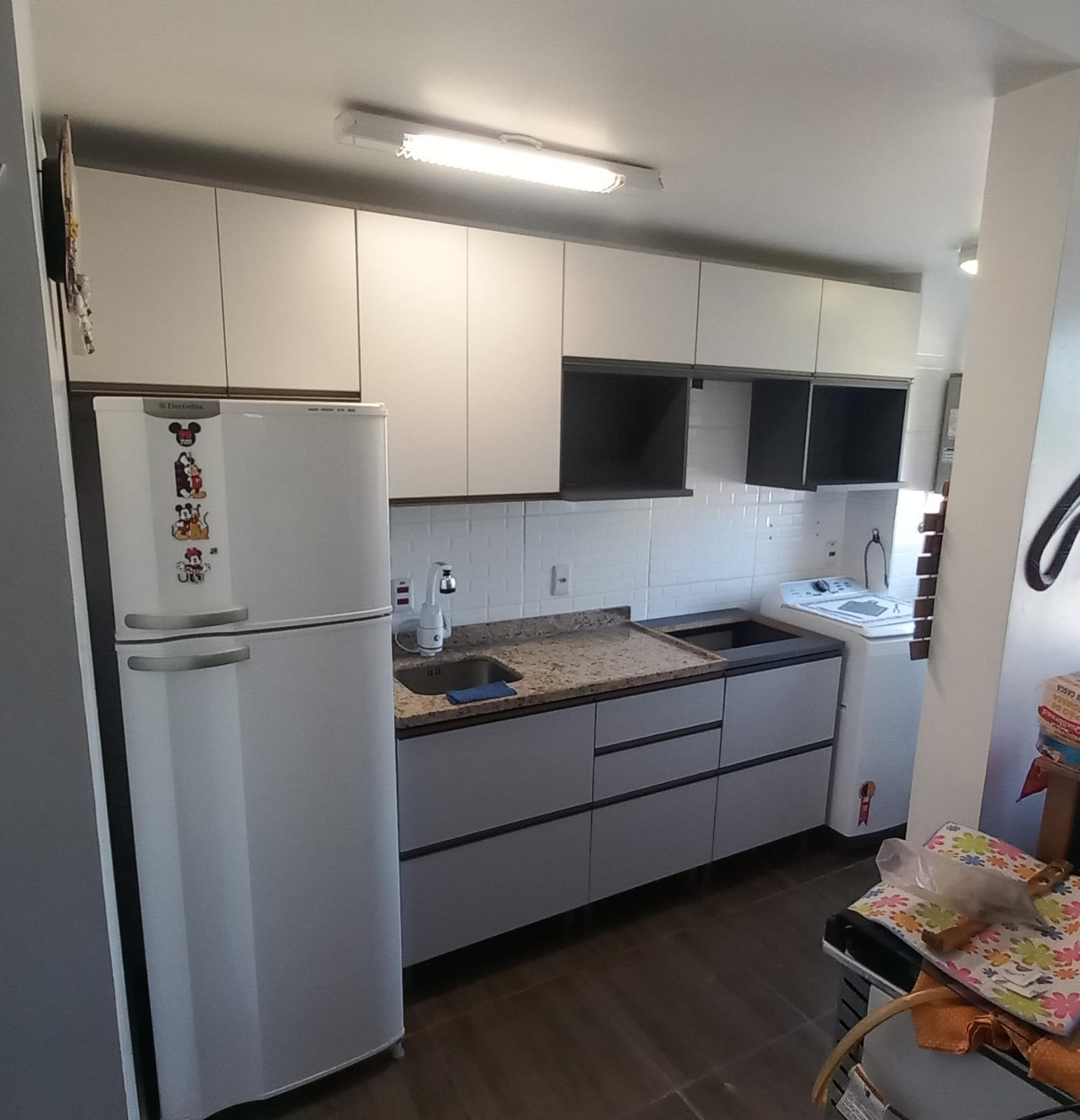 Cozinha planejada cinza com armários aéreos e bancada de pedra